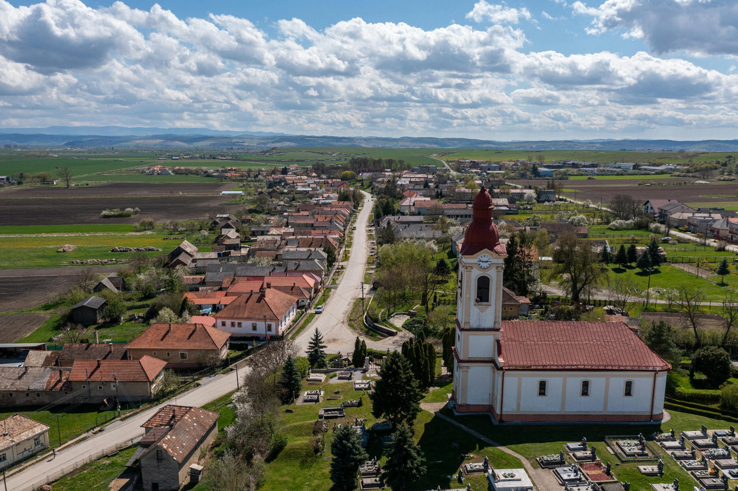 Scenic aerial view of Chanava village in Slovakia with church, fields, and rural landscape on a sunny day.